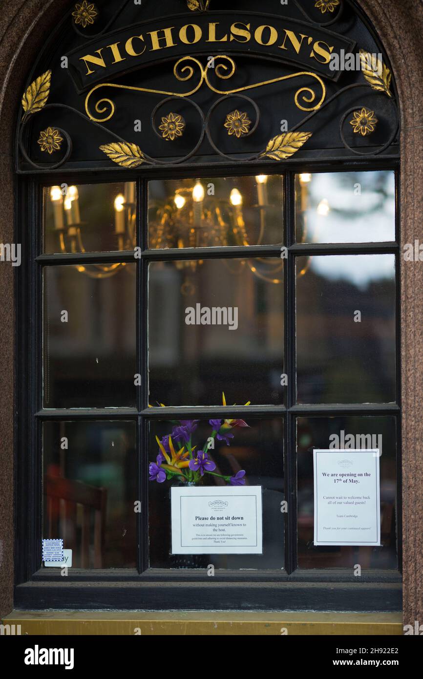 Blumen und Hinweise, die die Kunden über das Datum der Wiedereröffnung und über Anweisungen zu Gesundheitsmaßnahmen informieren, sind im Fenster eines Pubs in London zu sehen. Stockfoto