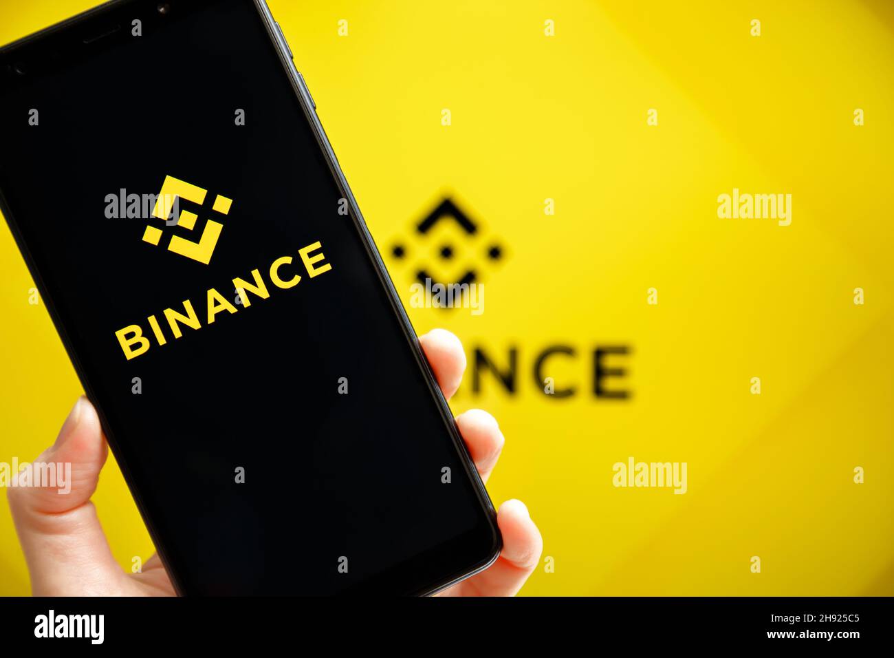 Ukraine, Odessa - Oktober, 9 2021: Hand hält Handy mit Binance App läuft auf dem Smartphone-Bildschirm mit Binance Logo im Hintergrund. Binance ist eine Kryptowährungs- und Handelsplattform Stockfoto