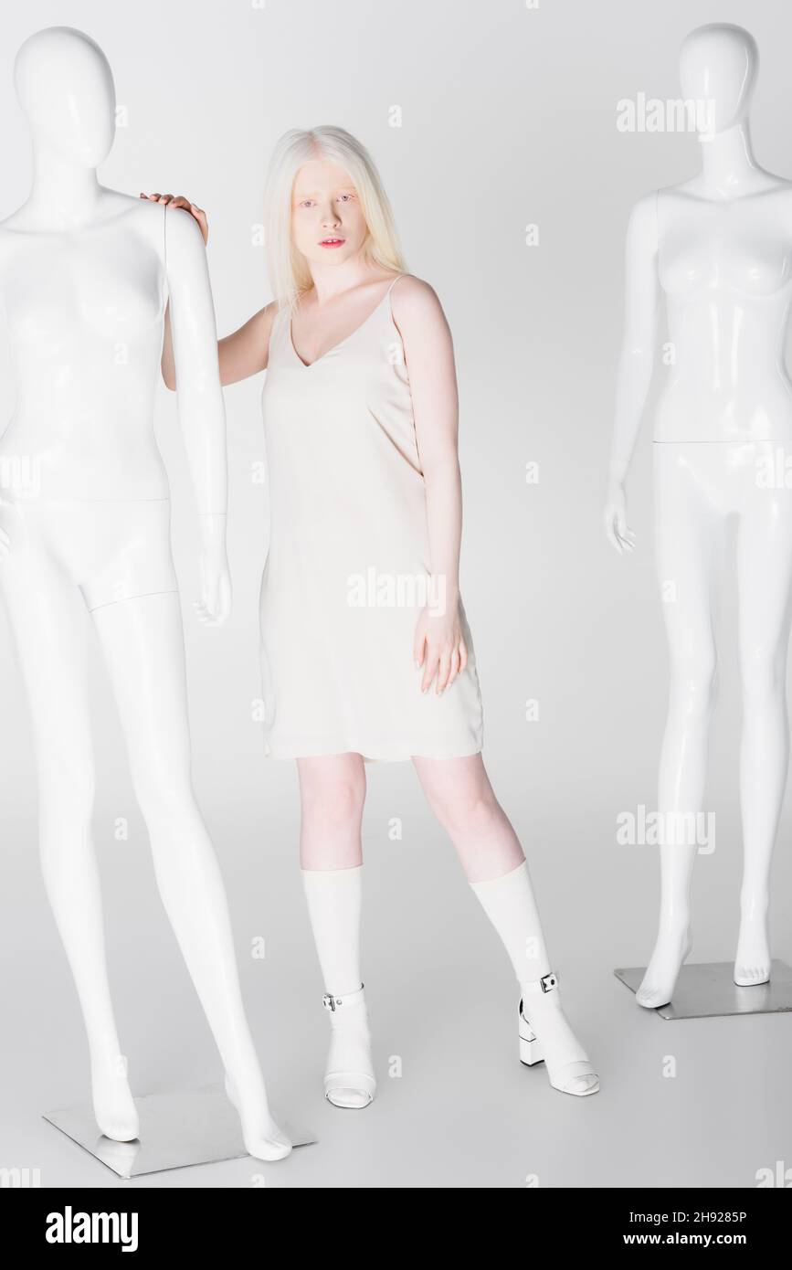 Volle Länge von Albino-Modell berühren Schaufensterpuppe auf weißem Hintergrund Stockfoto