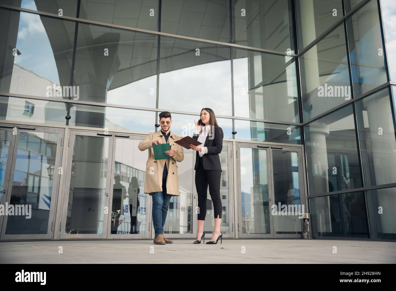 Zwei Geschäftsleute lächeln über tof, während sie am Telefon sprechen und die Pläne überprüfen Stockfoto