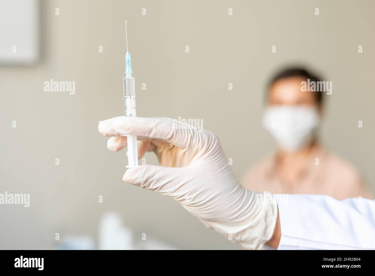 Anonyme Gesundheitsarbeiterin, die eine Patientin mittleren Alters impft. Unscharfer Hintergrund Stockfoto