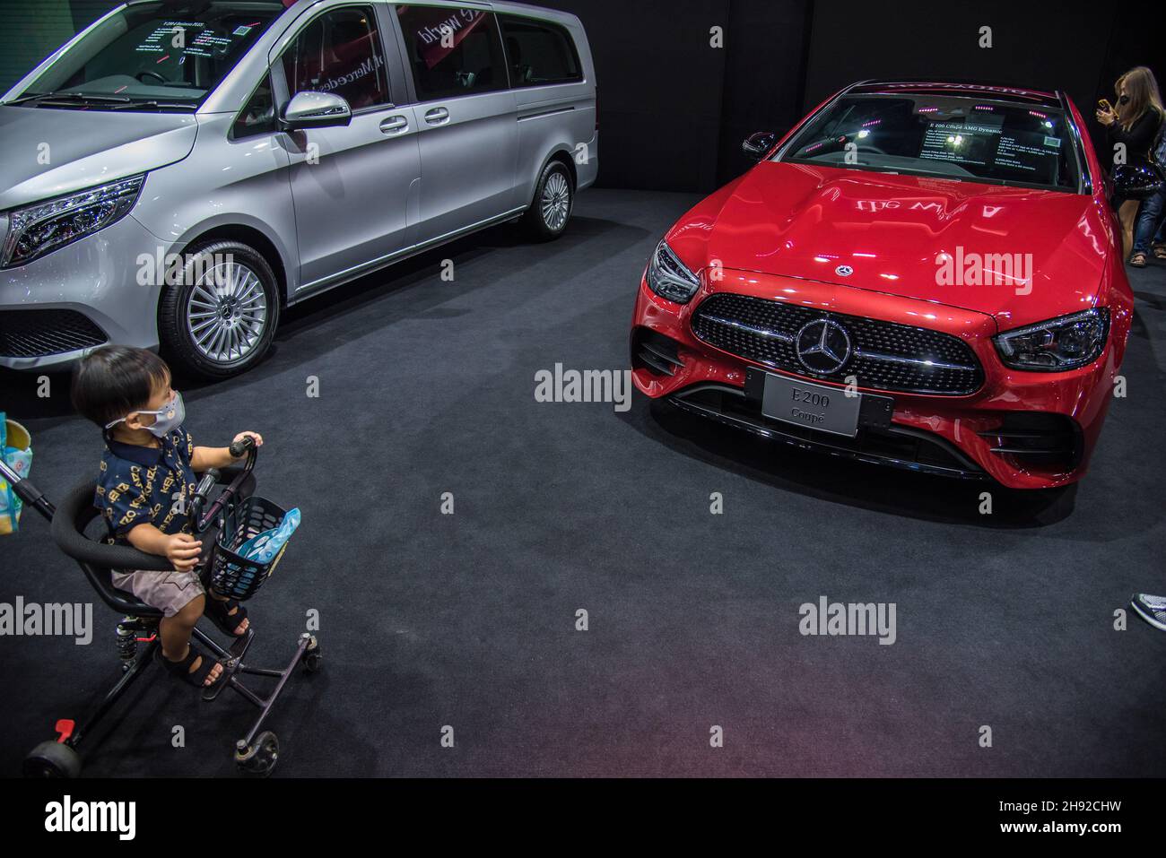 Nonthaburi, Thailand. 03rd Dez 2021. Ein Baby in einem Wagen, der in der Nähe eines Autos des Mercedes-Benz E200 Coupés auf der Motor Expo zu sehen ist.die Thailand International Motor Expo 2021 38th fand vom 1. Dezember 2021 bis zum 12. Dezember statt. 2021 mit 32 Automarken und 12 Motorradmarken sowie Elektrofahrzeugen, die gehalten wurden, um den Gesamtumsatz zu steigern und die Automobilindustrie nach der durch die anhaltende COVID-19-Pandemie verursachten Konjunkturverlangsamung wieder in den Handel zu bringen. Kredit: SOPA Images Limited/Alamy Live Nachrichten Stockfoto