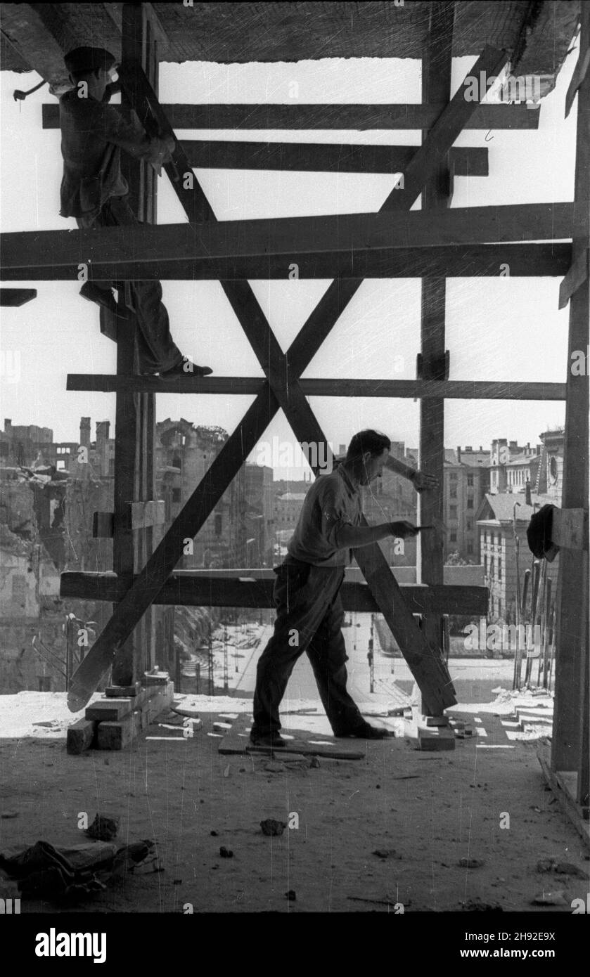 Warszawa, 1947-05. Odbudowa kamienic przy ulicy Traugutta, w rejonie placu Ma³achowskiego i ulicy Mazowieckiej. NZ. Robotnicy zbijaj¹ drewniane rusztowanie. W ind ulica Kredytowa, plac Ma³achowskiego i pozbawiony kopu³y koœció³ eangelicko-augsburski pw. Œwiêtej Trójcy. wb PAP Dok³adny dzieñ wydarzenia nieustalony. Warschau, Mai 1947. Der Wiederaufbau von Mietshäusern in der Traugutta Straße, in der Nähe des Malachowskiego Platzes und der Mazowiecka Straße. Im Bild: Arbeiter, die ein Holzgerüst aufbauten. Im Hintergrund die Kredytowa Straße, der Malachowskiego Platz und die evangelisch-Augsburger Heilige Dreifaltigkeit Chur Stockfoto