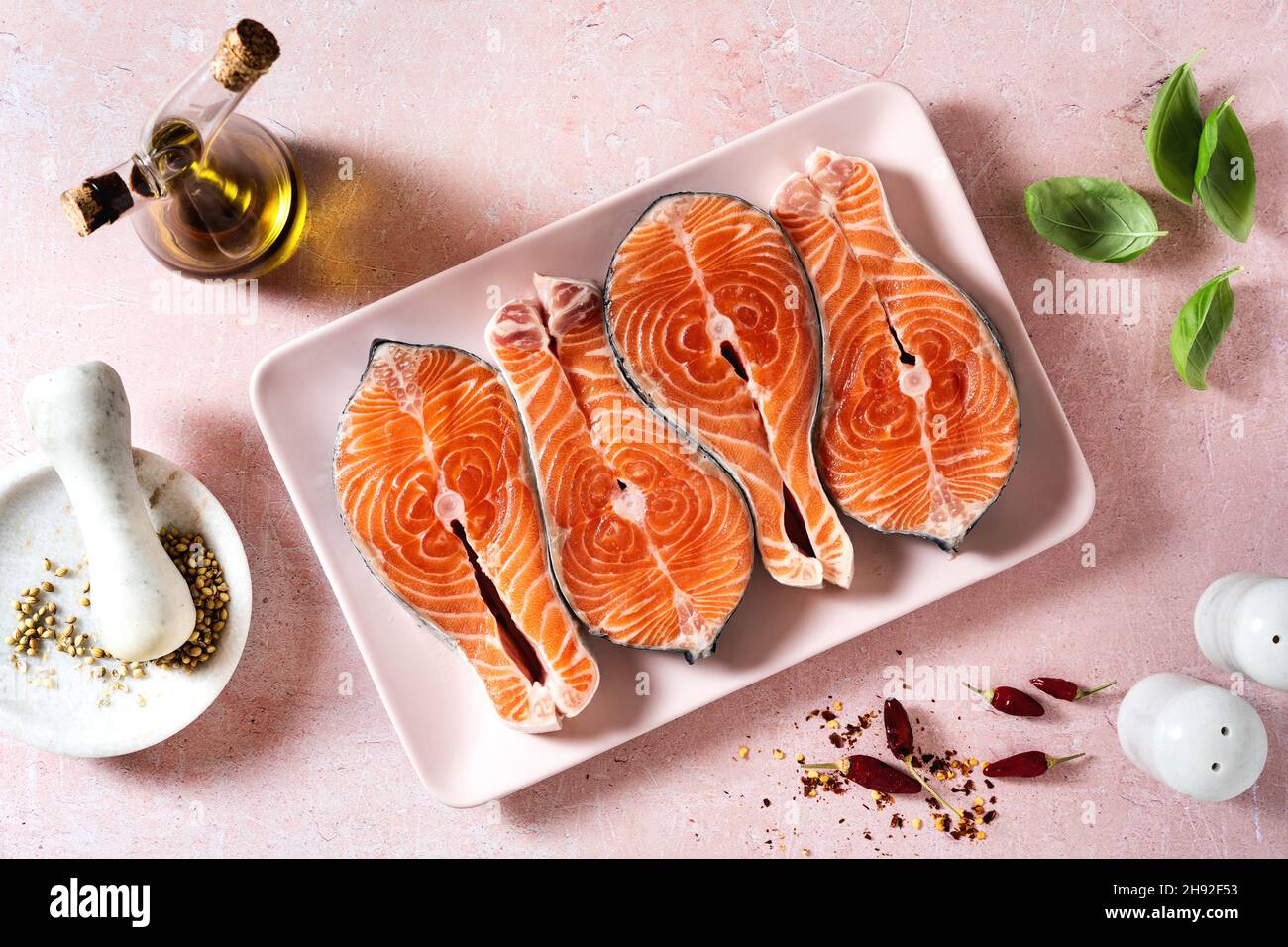 Frische Lachsscheiben auf einem rosafarbenen Teller auf einem rosafarbenen Tisch, fertig zum Kochen Stockfoto