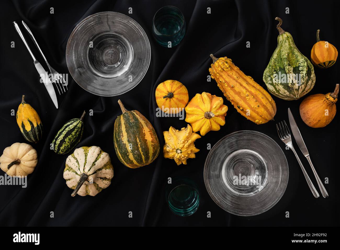 Der Tisch ist mit einer schwarzen halloween Tischdecke mit Kürbissen und einem Set Teller und Besteck bedeckt Stockfoto