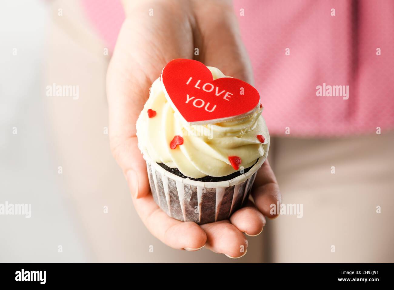 Mädchen hält herzförmigen Kuchen mit der Aufschrift Ich liebe dich. Cupcake in Herzform, Nahaufnahme Stockfoto