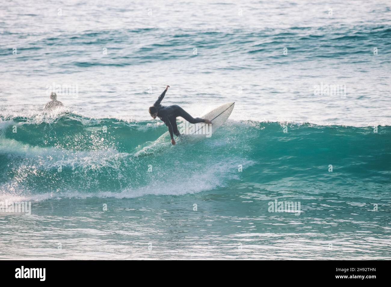 Surfer auf einer blauen Welle an sonnigen Tagen in Ericeira in Portugal. Stockfoto