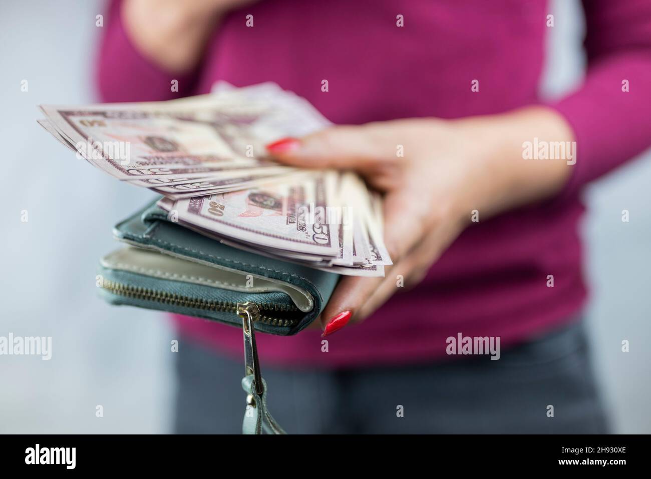 Das Mädchen hält sich in den Händen und zählt die Geldmittel in der Brieftasche Stockfoto