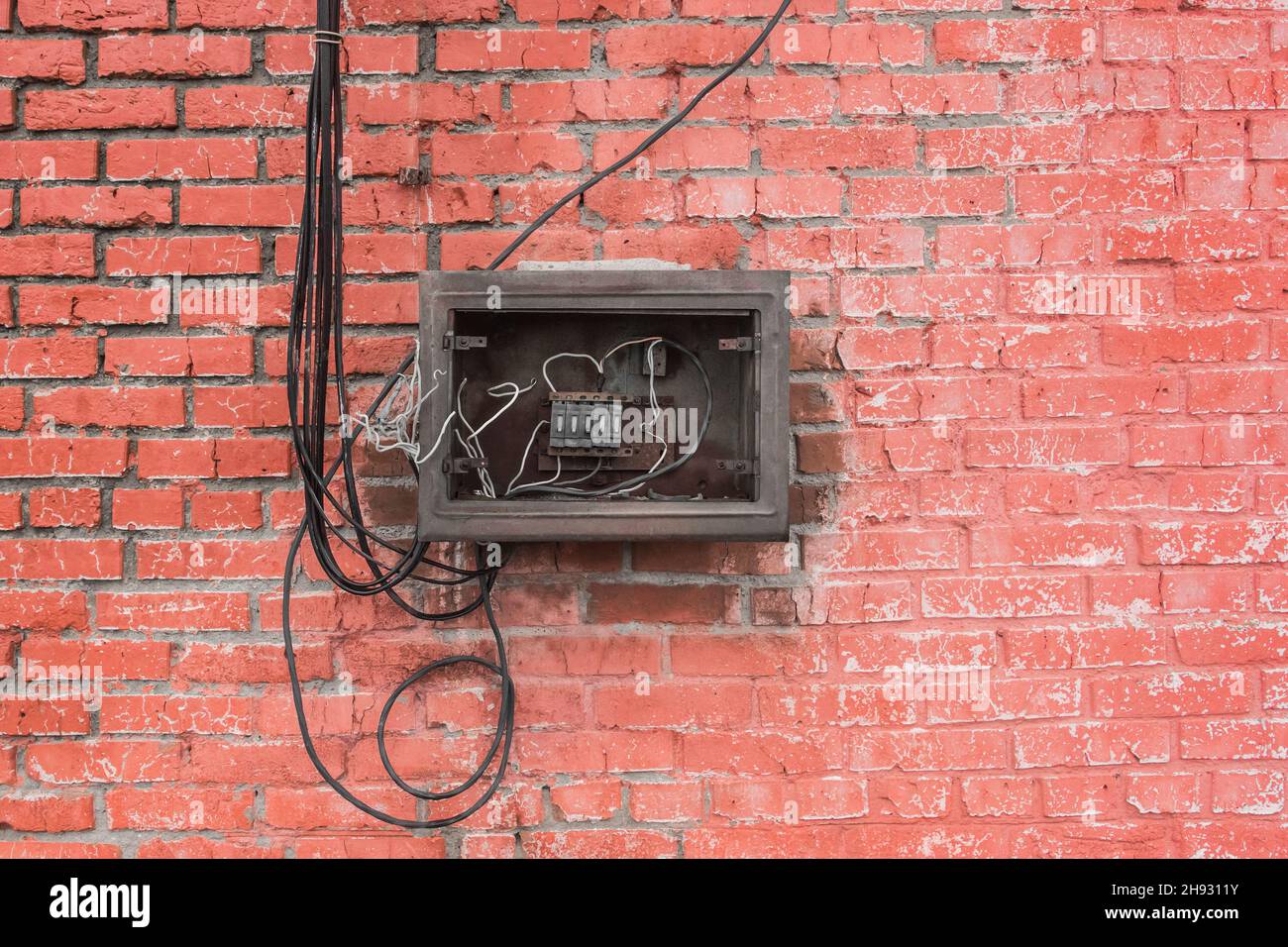 Die Nische der alten defekten elektrischen Platte der Schublade an der Wand. Industrielle Stromregelung Für Den Abbruch. Stockfoto