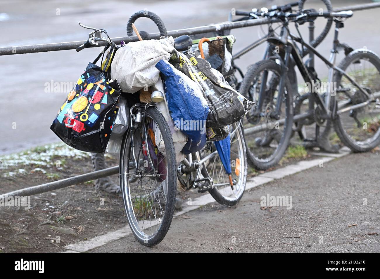 München, Deutschland. 03rd Dez 2021. Themenfoto Armut. Ein Fahrrad lehnt sich im Münchner Hofgarten an ein Geländer, auf dem sich viele Tragetaschen befinden, die scheinbar einem Obdachlosen gehören. Kredit: dpa/Alamy Live Nachrichten Stockfoto