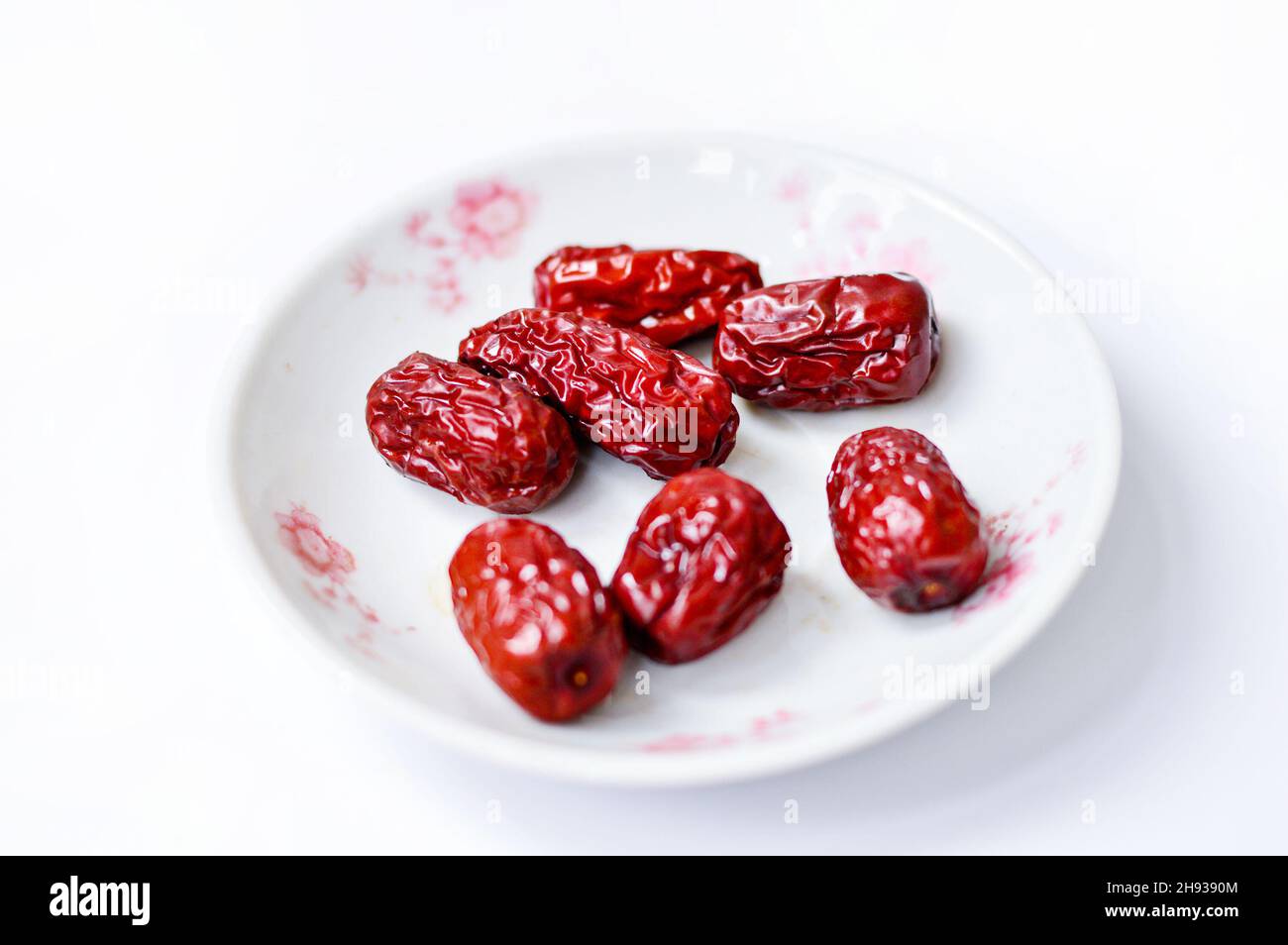 Getrockneter chinesischer roter Jujube in einem Teller, isoliert auf weißem Hintergrund. Stockfoto