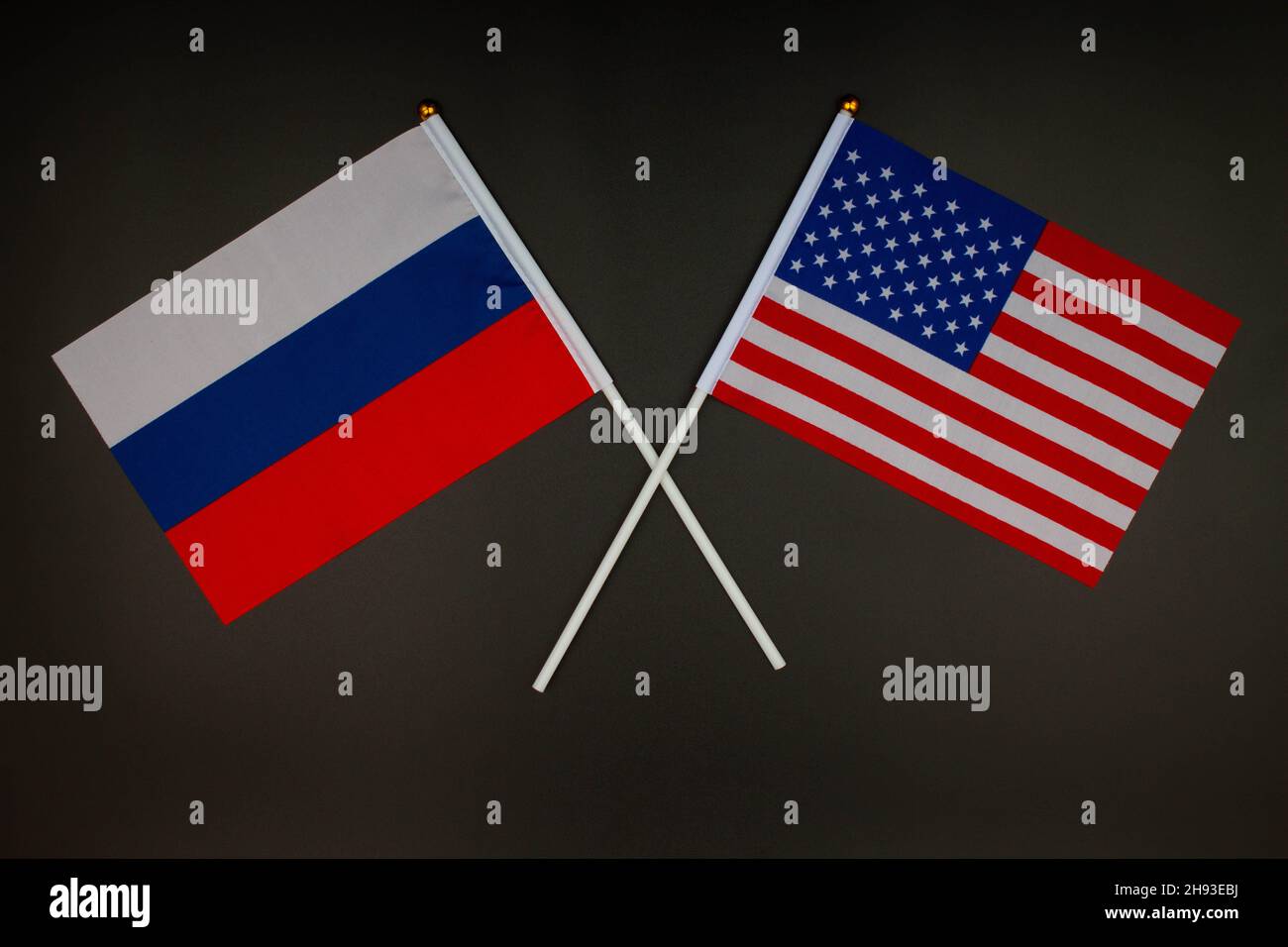 Die russische Flagge und die US-Flagge kreuzen sich auf schwarzem Hintergrund. Russland gegen USA. Treffen zwischen den Präsidenten Russlands und der Vereinigten Staaten Stockfoto
