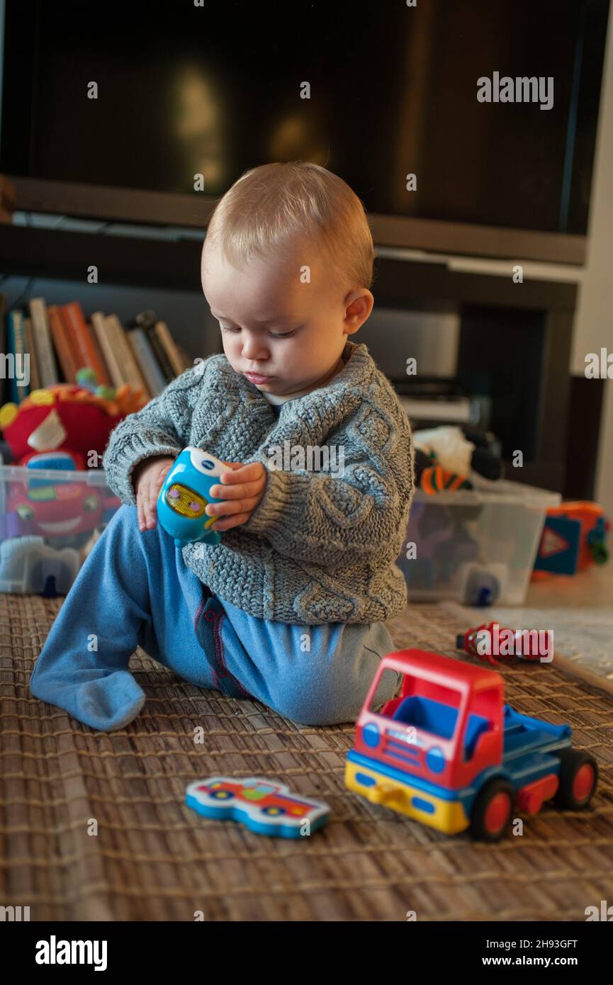 Ein kleines Mädchen (ca. 10 Monate alt) studiert zu Hause ein Spielzeug. Stockfoto