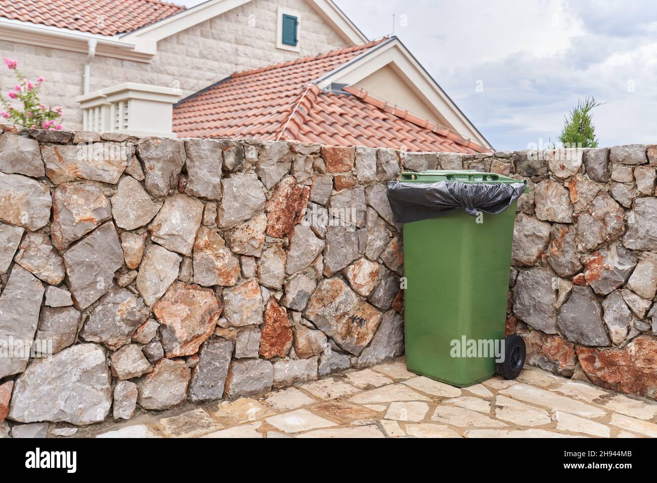 Grüner Abfalleimer neben dem Haus auf dem Hinterhof. Stockfoto