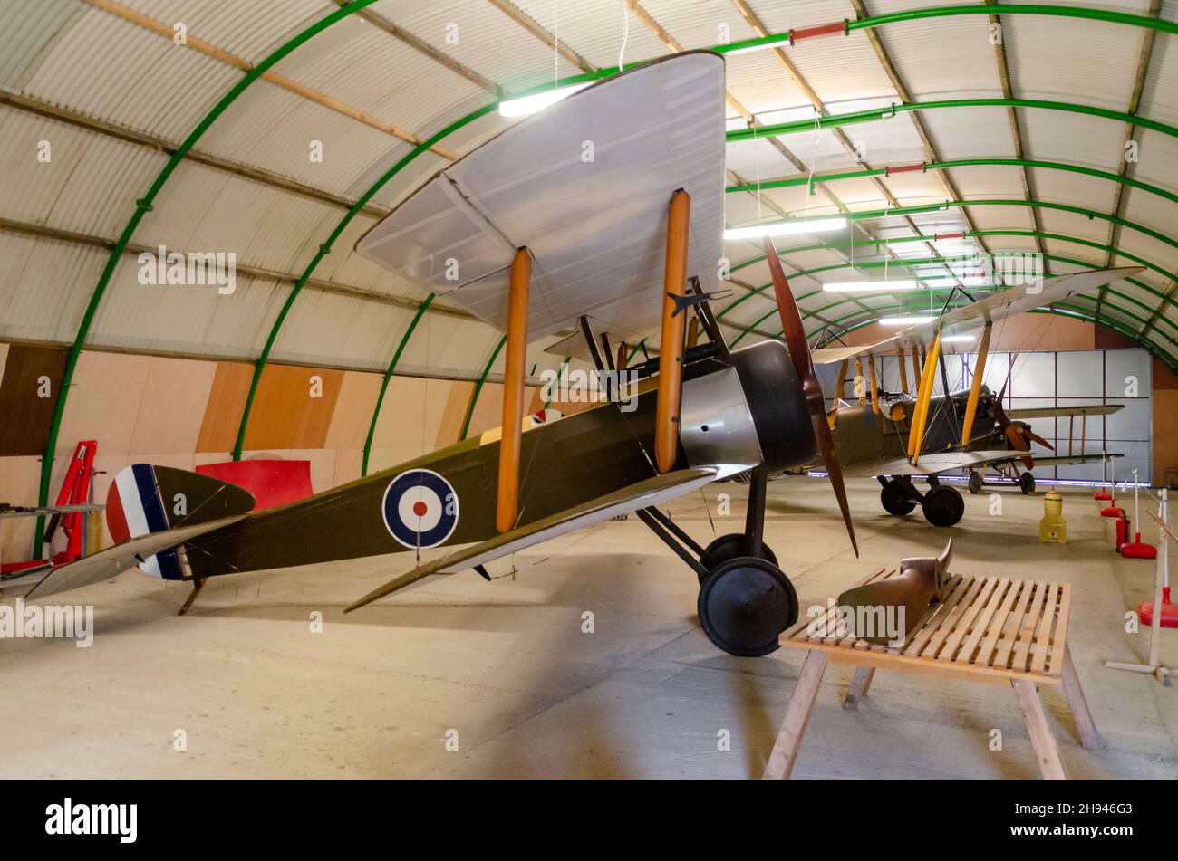 Replik Sopmit Kampfflugzeug aus dem Ersten Weltkrieg in einem neuen Hangar auf dem historischen Flugplatz Stow Maries, mit flugfähigen Flugzeugen darüber hinaus Stockfoto