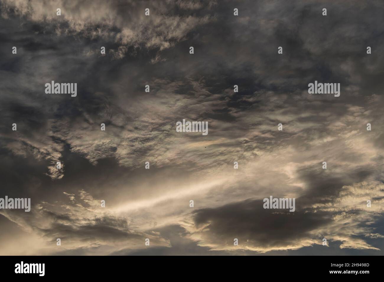 Dunkle, komplizierte Wolken, die von unten kurz vor Sonnenuntergang beleuchtet werden. Lichtwellen unter der Wolkendecke. Sommerwetter in Queensland, Australien. Stockfoto