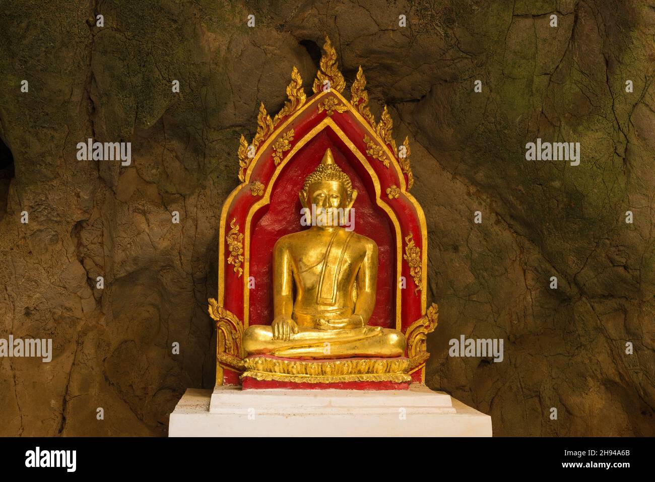 PHETCHABURI, THAILAND - 13. DEZEMBER 2018: Eine der vielen Skulpturen des Buddha vor dem Hintergrund einer Steinmauer. Höhlentempel des Wat Tham KH Stockfoto