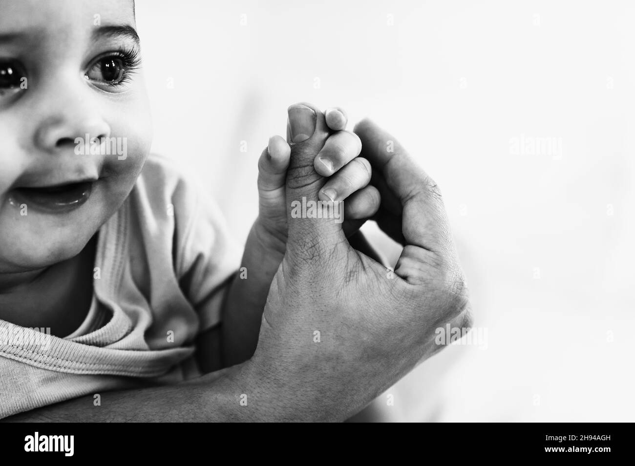 Nahaufnahme eines kleinen Babys mit dem Daumen der Mutter - Familien- und Mutterschaftskonzept - Schwarz-Weiß-Schnitt Stockfoto