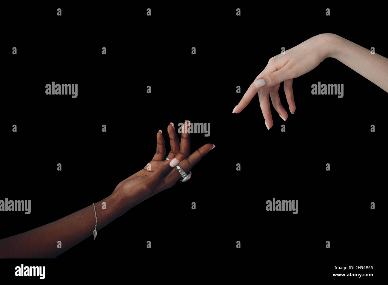 World Humanitarian Day. Caucasian white and African American black hand reaching out to each other on black background. Stockfoto