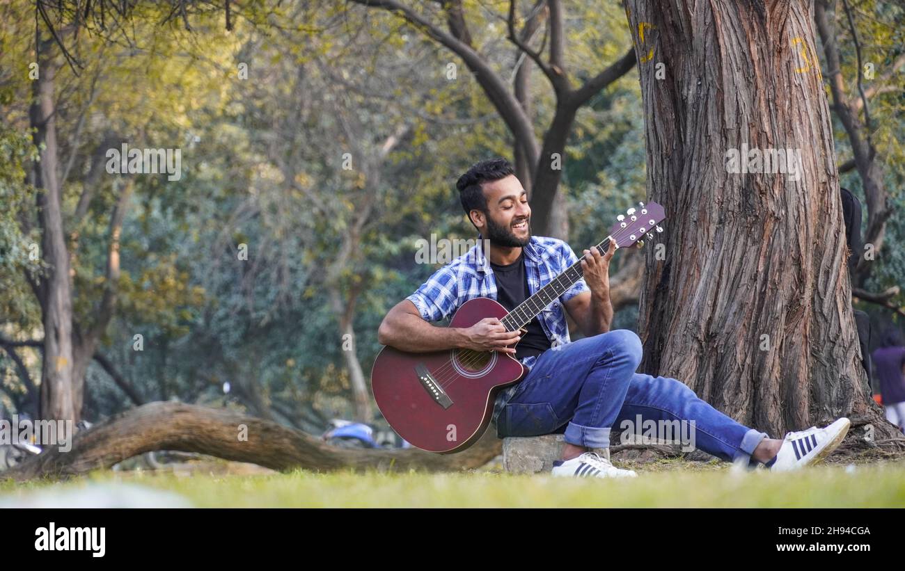 Kleiner Junge mit seiner Gitarre und Gitarre spielen im Park Stockfoto