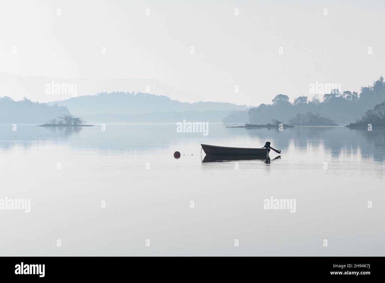 Fischerboot auf dem nebligen loch in der Morgendämmerung - Loch Lomond, Schottland, Großbritannien Stockfoto