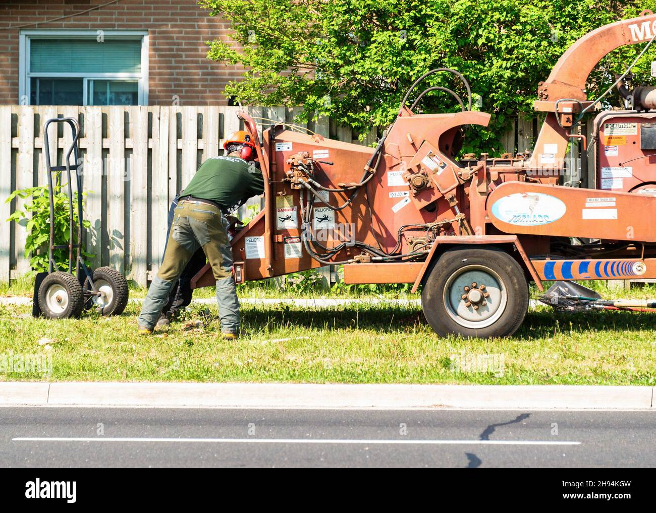 Ein Mann arbeitet in Baum Mulcher-Maschine im Vorderhaus von einem privaten Zaun umgeben.Nov. 22, 2021 Stockfoto