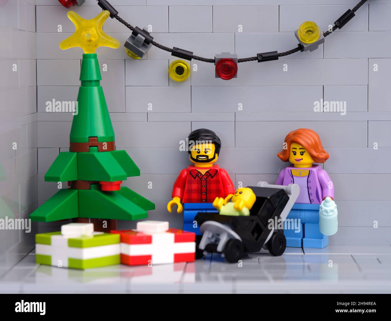 Tambow, Russische Föderation - 01. Dezember 2021 Ein Lego-Vater, eine Mutter und ein Baby minifiguren, die neben einem Weihnachtsbaum stehen, der Geschenke darunter hat. Stockfoto