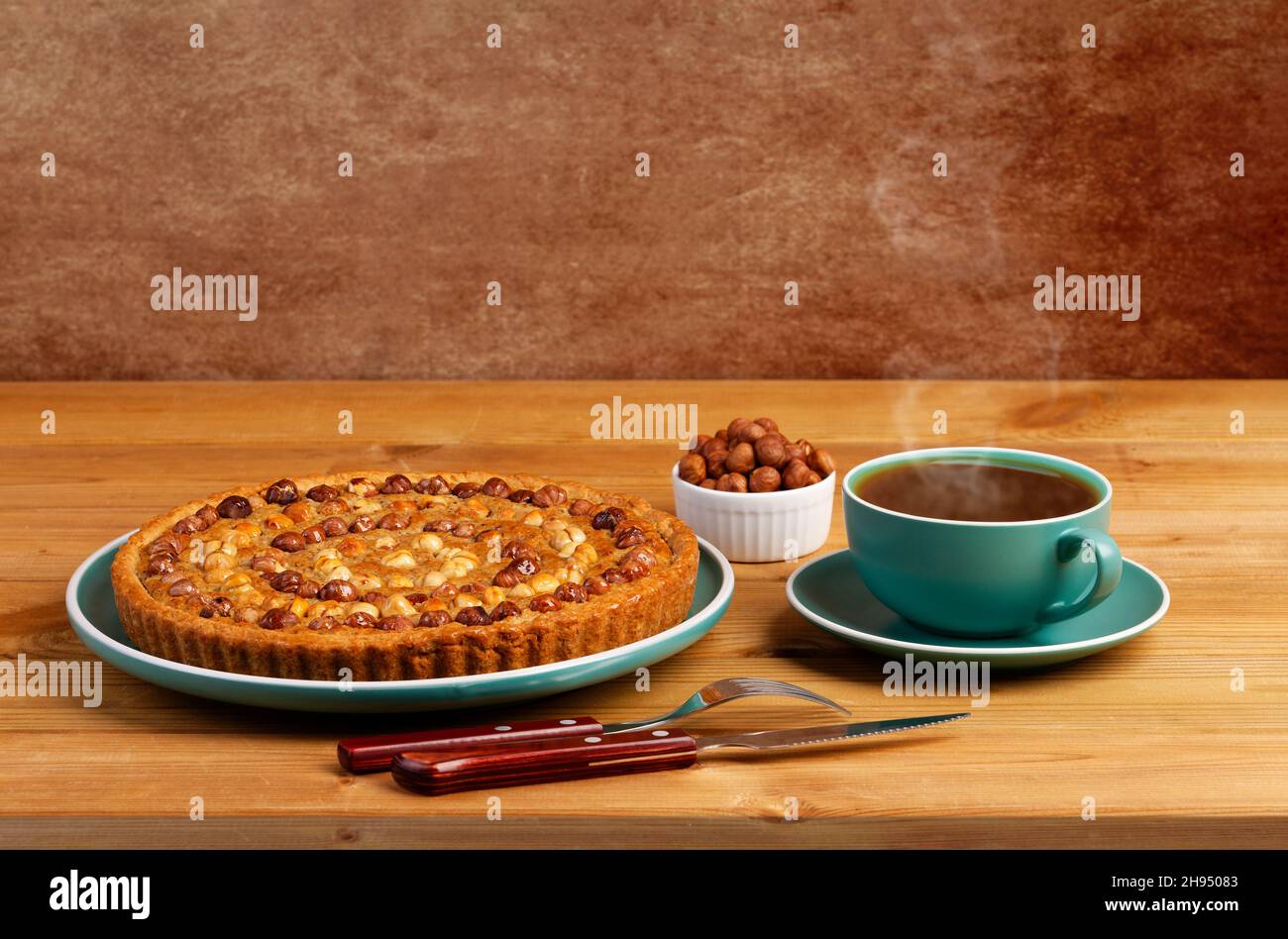 Hausgemachter Kuchen mit Nüssen Haselnuss und einer Tasse Tee auf einem Holztisch dekoriert. Copyspace. Stockfoto