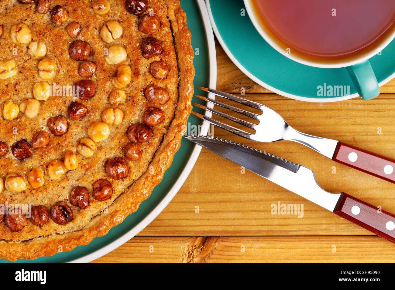 Schließenp hausgemachte Kuchen mit Nüssen Haselnuss und einer Tasse Tee auf einem Holztisch dekoriert. Draufsicht. Stockfoto