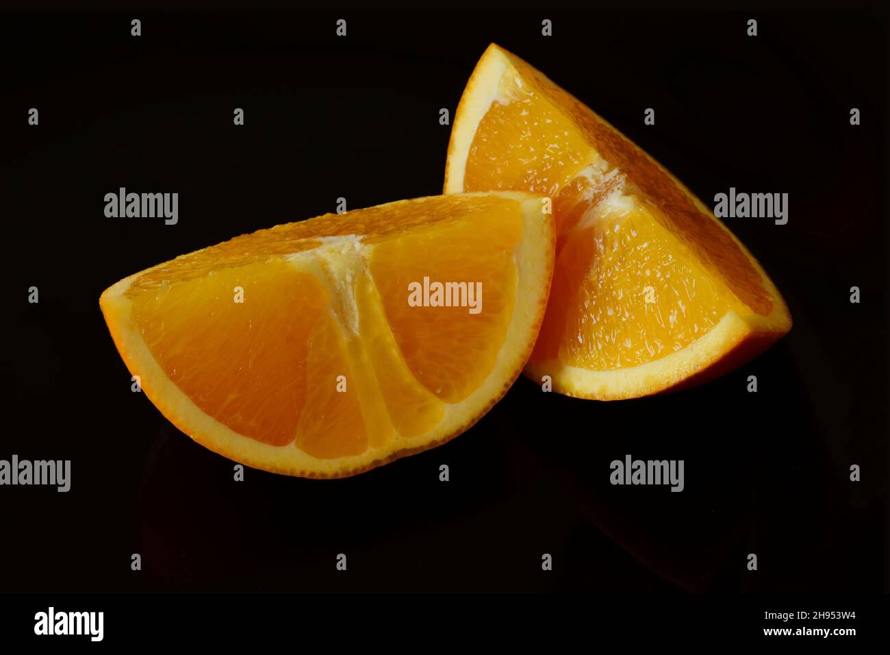 Isolierte Scheiben reifer orangefarbener Früchte in der Makroansicht. Schwarzer Hintergrund. Weiße und gelbe Orangenschale. Vitamin und gesundes Esskonzept. Stillleben Bild Stockfoto