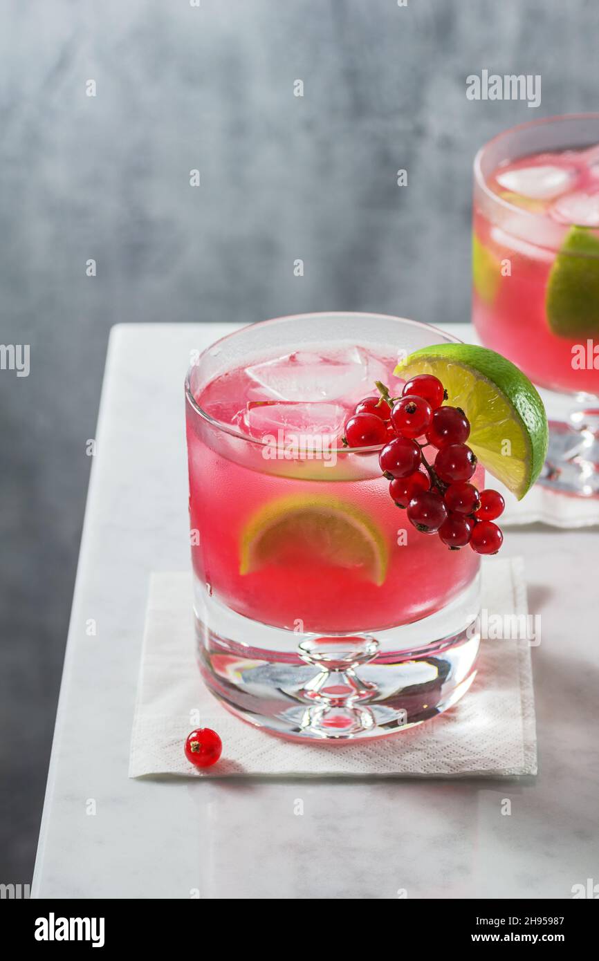 Caipirinha Cocktail Drink mit roter Johannisbeere und Beerenarnish auf minimalistischem Marmor-Counter-Top Stockfoto