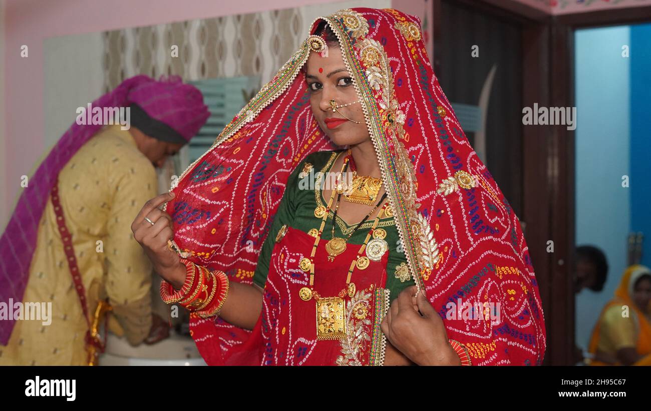 21. November 2021 Reengus, Rajasthan, Indien. Rajasthani junge Frau in roter Tracht mit traditionellem Schmuck und bunten Armreifen. Stockfoto