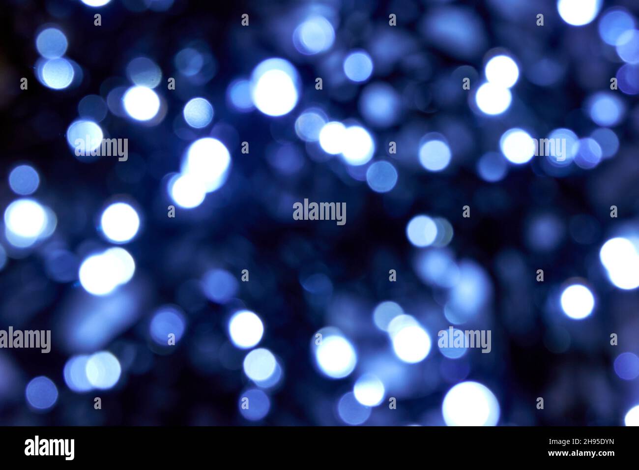 Kaltblaue Farbe. weihnachtliche weiße und blaue Lichter auf schwarzem Hintergrund. Verschwommene abstrakte blaue Glitzerstruktur. Verwischen Sie Bokeh-Glitzer. Stockfoto