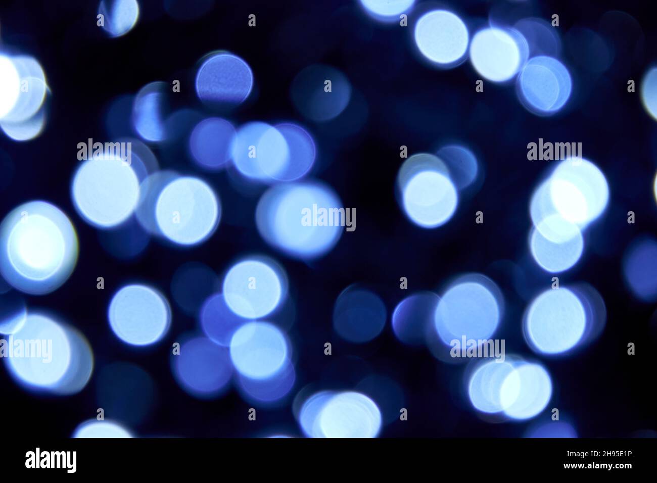 Unschärfe Bokeh weihnachten große blaue Lichter auf schwarzem Hintergrund. Verschwommene abstrakte blaue Glitzerstruktur. Blaue Bokeh Glitzer Tapete für Weihnachten. Stockfoto