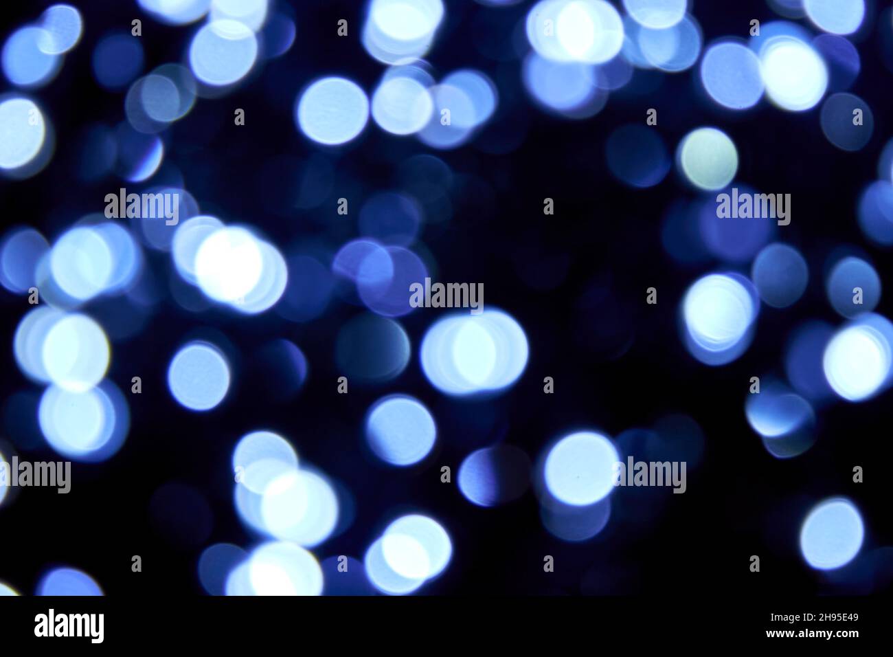 Unschärfe Bokeh weihnachten große blaue Lichter auf schwarzem Hintergrund. Verschwommene abstrakte blaue Glitzerstruktur. Blaue Bokeh Glitzer Tapete für Neujahr. Stockfoto