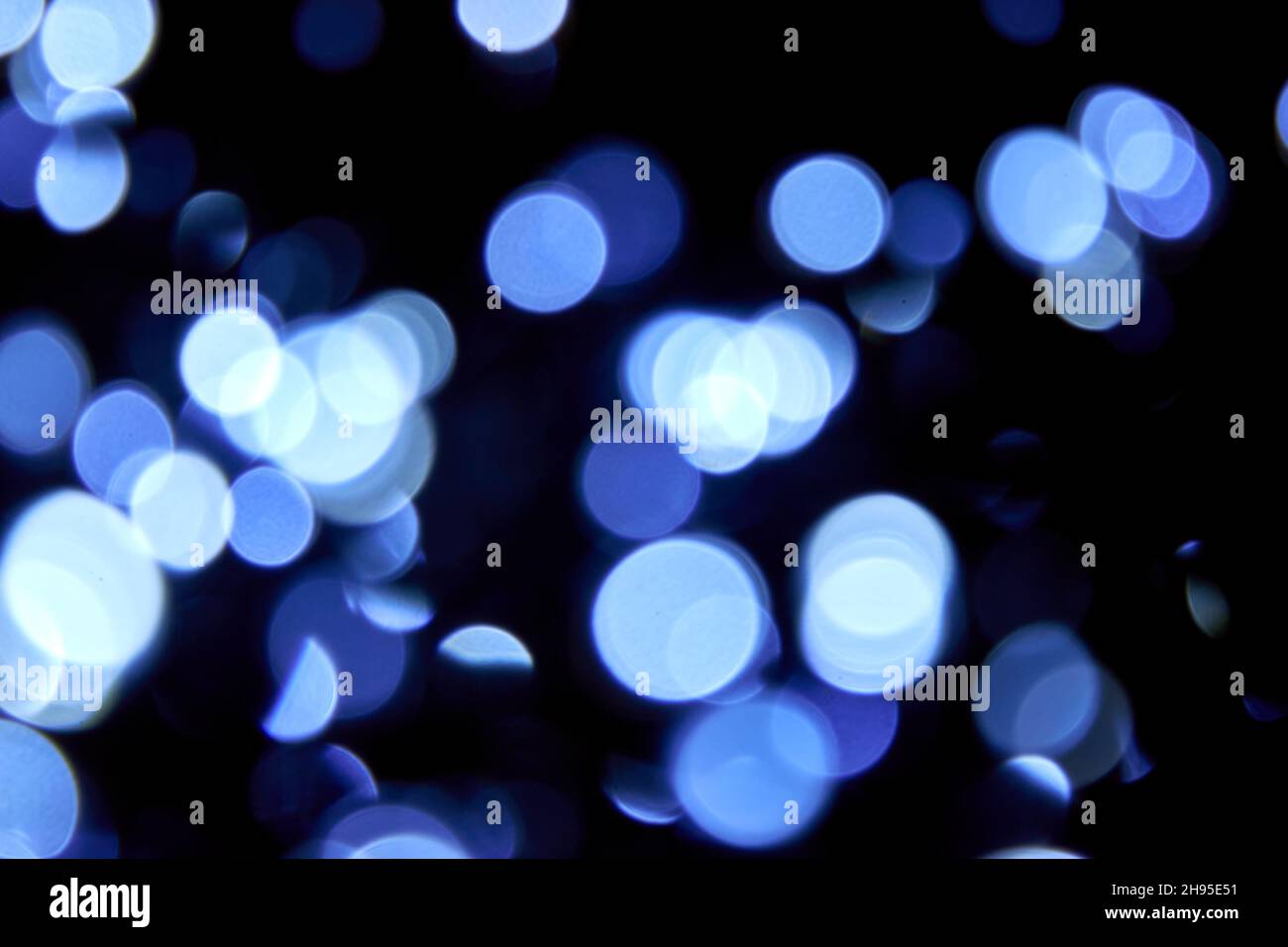 Unscharfsinnige Bokeh weihnachten große blaue Lichter auf schwarzem Hintergrund. Verschwommene abstrakte blaue Glitzerstruktur. Blaue Bokeh Glitzer Tapete für Weihnachten. Stockfoto