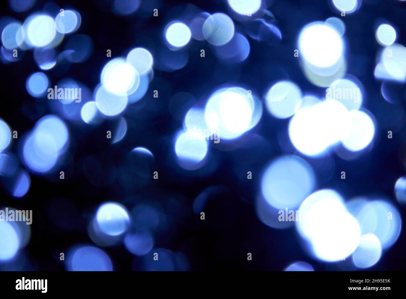Eine Menge unscharfsinnig Bokeh weihnachten große blaue und weiße Lichter auf schwarzem Hintergrund. Verschwommene abstrakte blaue Glitzerstruktur. Blaue Bokeh Glitzertapete Stockfoto