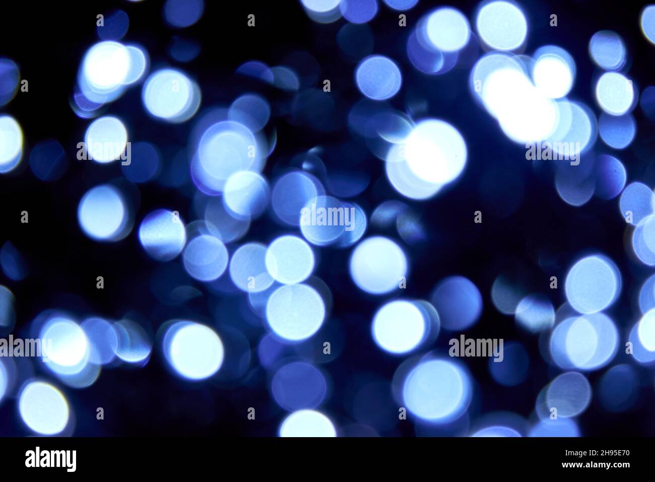 Verschwommene abstrakte blaue Glitzerstruktur. Viele Unschärfe-Bokeh weihnachten blaue Lichter auf schwarzem Hintergrund. Blaue Glitzer-Tapete für Weihnachten, Neujahr Stockfoto