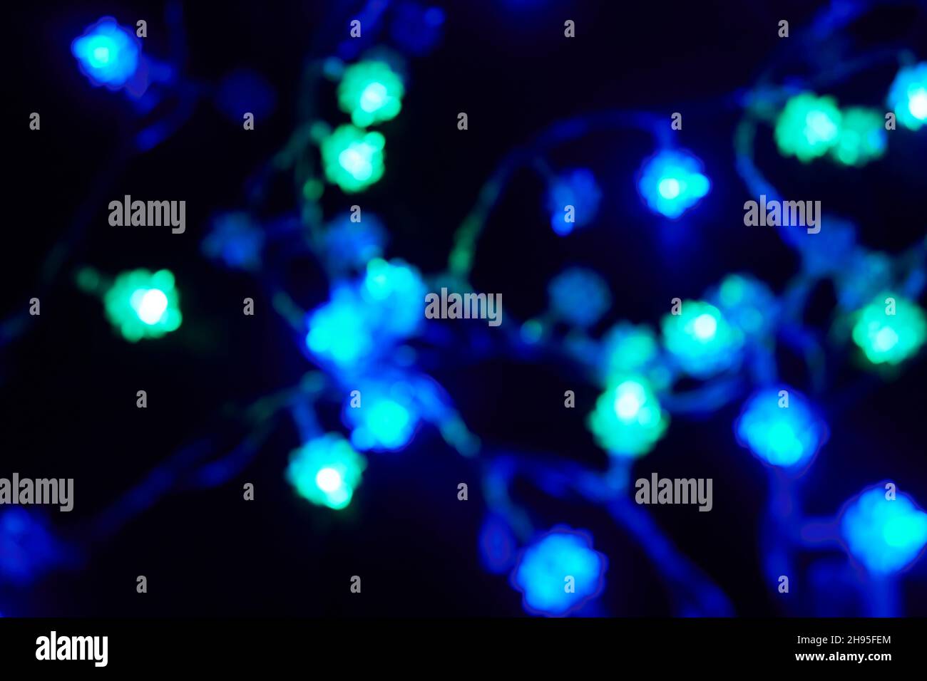 Defokussed Bokeh weihnachten blau und grün Lichter auf schwarzem Hintergrund. Verschwommene abstrakte Glitzerstruktur. Blur Bokeh Glitzer Tapete für Weihnachten. Stockfoto