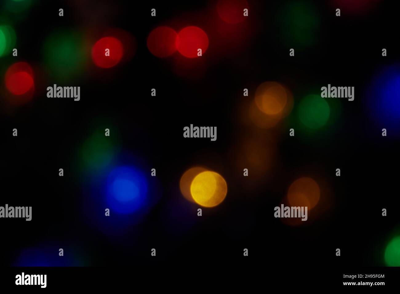 Defokussierte, große Bokeh-Lichter mit bunten Farben auf schwarzem Hintergrund. Verschwommene abstrakte blaue, grüne, rote, orangefarbene Flecken. Hintergrund für unscharfe Bokeh-Flecken Stockfoto