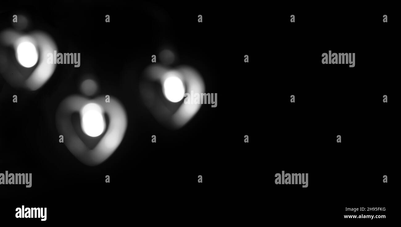 Schwarzes Banner mit Platz für Text. Drei weiße, verschwommene Lichter in Form eines Herzens. Copyspace. Stockfoto
