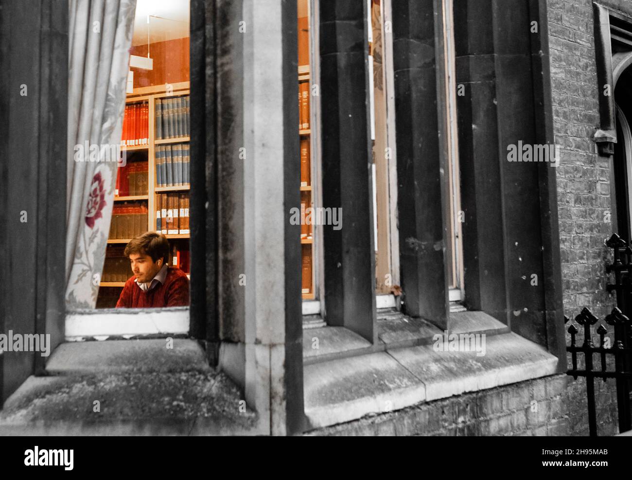 Ein Undergraduate an der University of Cambridge studiert an einem kalten Dezemberabend allein in einem Raum in einem alten Gebäude mit buchgesäumten Wänden. Nach Stockfoto