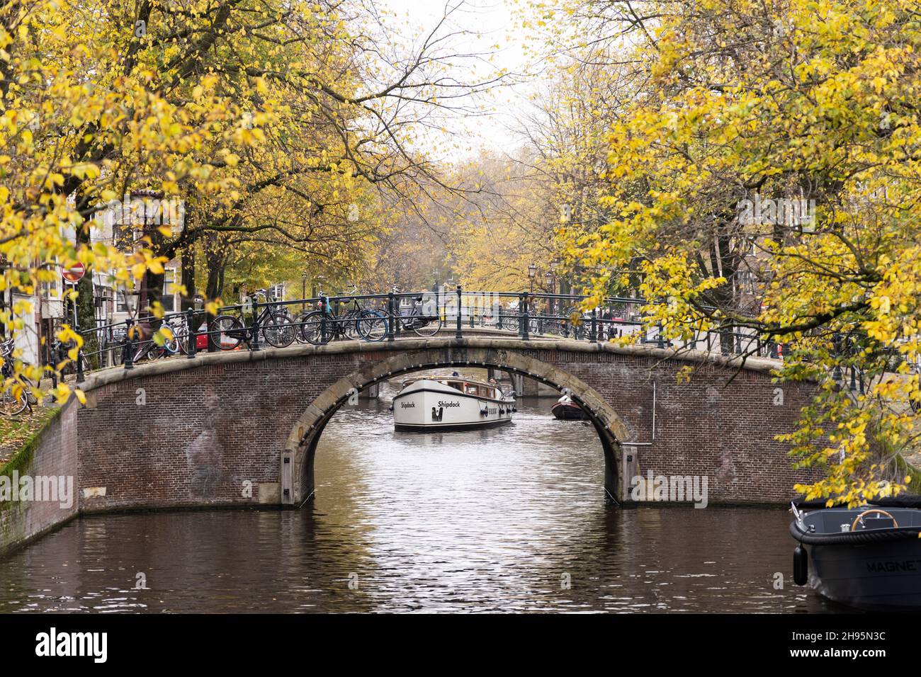 Ein Boot ist an einem Novembertag unter einer der sieben Brücken des Reguliersgracht-Kanals in Amsterdam, Niederlande, zu sehen. Stockfoto