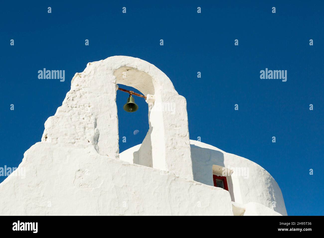 Glocke und Mond durch einen Gebäudebogen in Mykonos, Griechenland Stockfoto