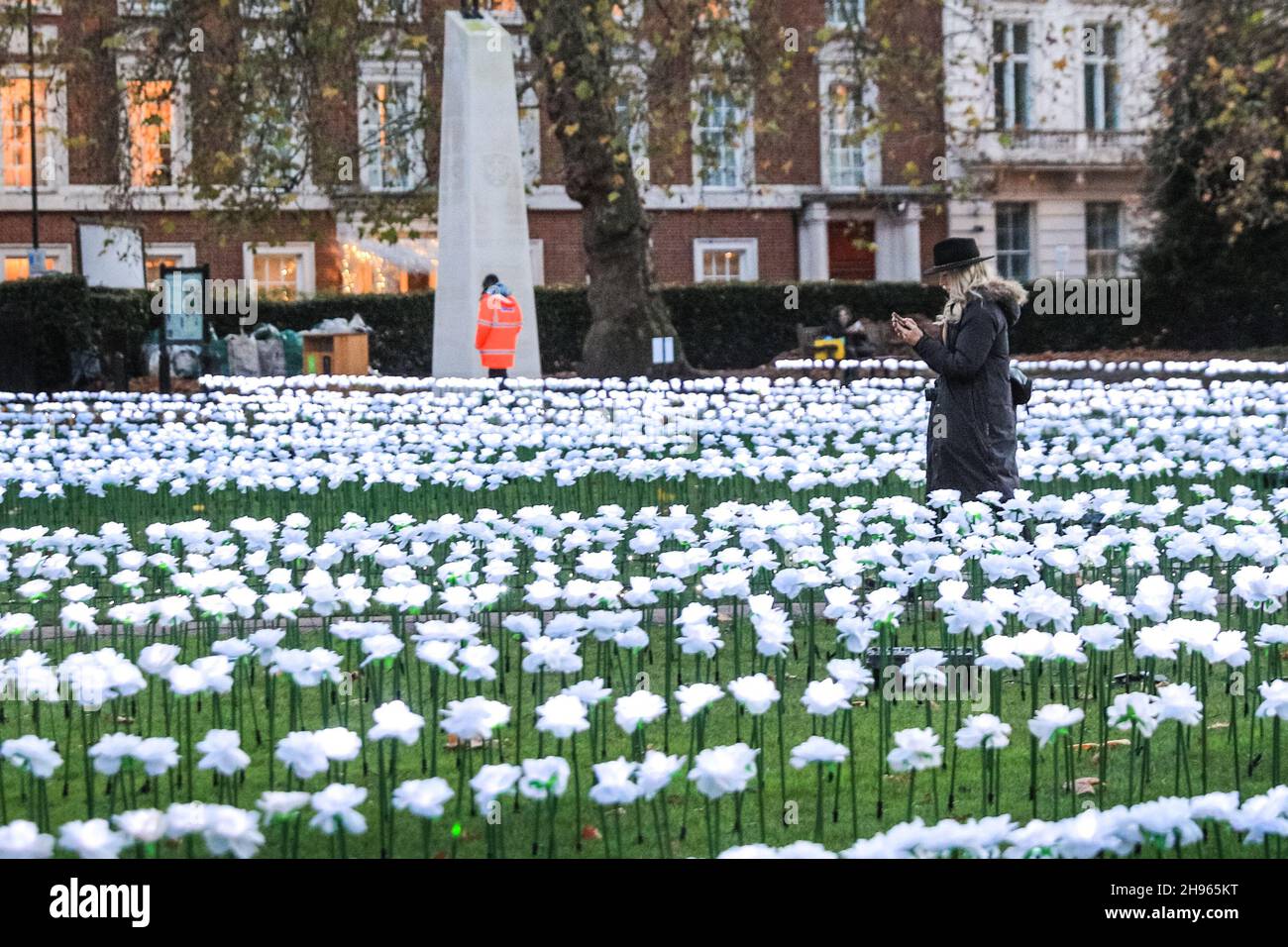 London, Großbritannien. 4th Dez 2021. Die Menschen gehen durch den Ever After Garden, der 25.000 strahlend weiße Rosen am Grosvenor Square zeigt. Die kostenlose Lichtinstallation ist bis zum 23rd. Dezember geöffnet und sammelt Mittel für die Royal Martsden Cancer Charity. Die Besucher können auch ihre eigene beleuchtete Rose einem geliebten Menschen widmen, als Gegenleistung für eine Spende an die Wohltätigkeitsorganisation. Kredit: Imageplotter/Alamy Live Nachrichten Stockfoto