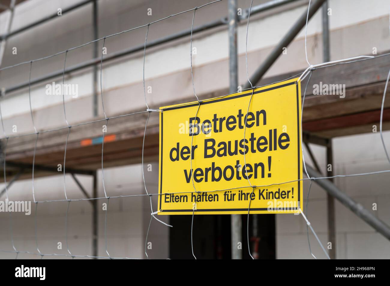 Ein Schild auf dem Bauzaun mit der deutschen Aufschrift , das Betreten der Baustelle ist verboten, Eltern haften für ihre Kinder Stockfoto