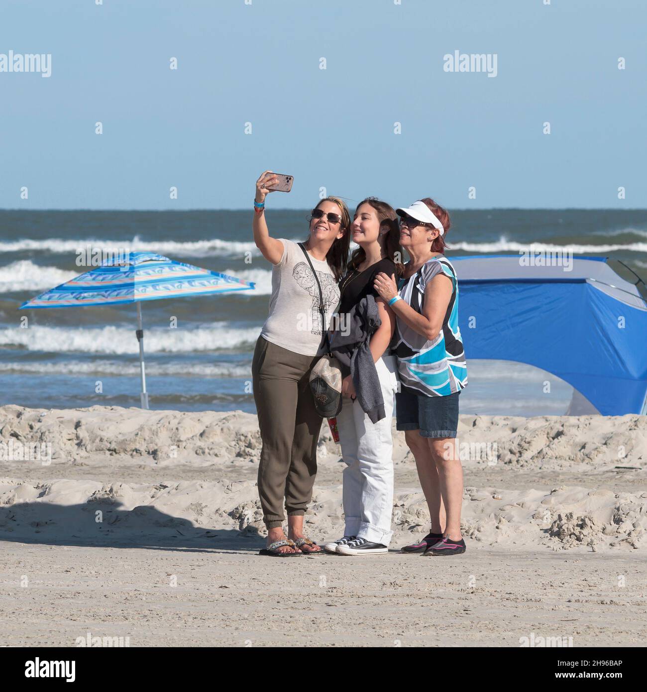 Drei Frauen machen ein Gruppen-Selfie mit einem Handy an einem Strand in Port Aranas, Texas, USA. Stockfoto