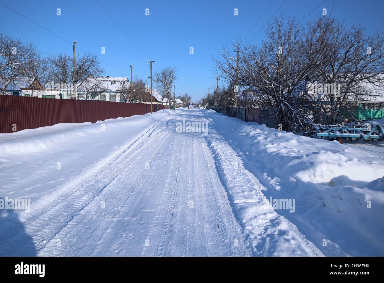 Wunderschöne Aussicht auf leere verschneite Straße im Winter. Schneeverwehungen auf beiden Seiten der Straße. Stockfoto