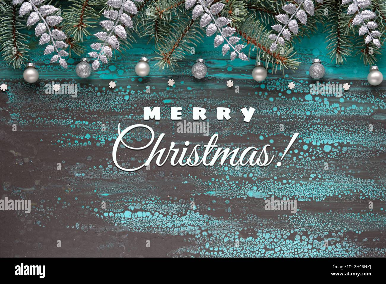 Silberner Weihnachtsrand mit Tannenzweigen, Glaskugeln und exotischen Farnblättern. Text-Frohe Weihnachten. Flüssiger abstrakter Acryl-Hintergrund in Türkis Stockfoto