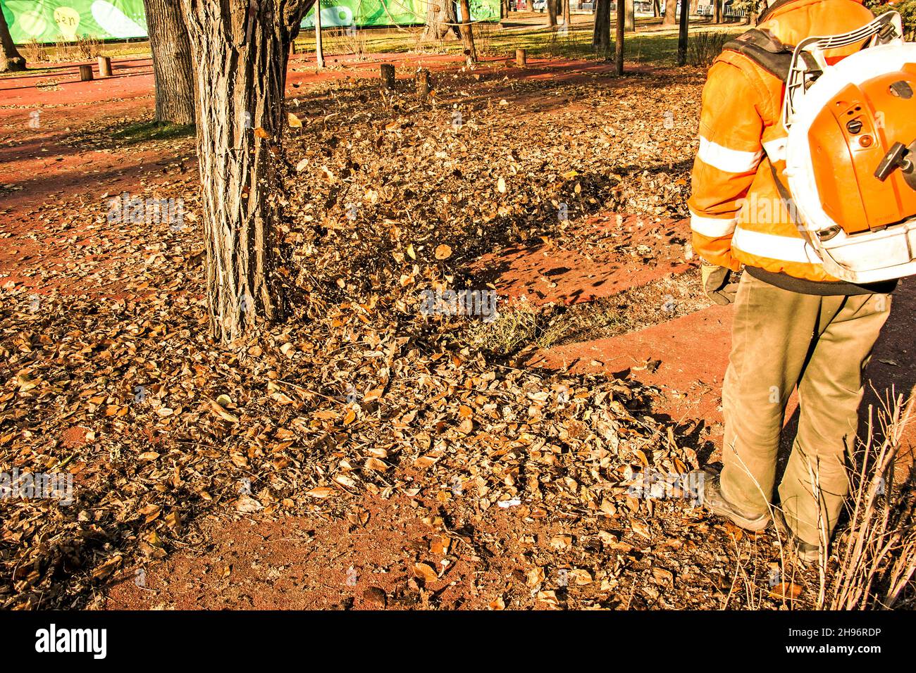 Trockene Blätter mit einer Windmühle reinigen. Ein kommunaler Arbeiter säubert den Stadtpark. Stadtparks für den Winter vorbereiten. Stockfoto